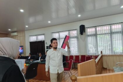 Terdakwa (JA) mengenakan kemeja putih berlengan panjang